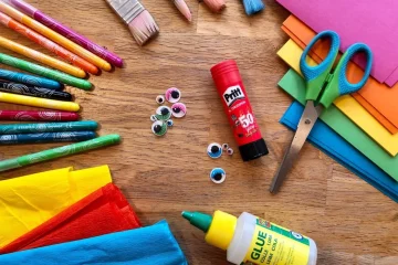 Stiften schaar gekleurd papier lijm knutselmaterialen op een tafel
